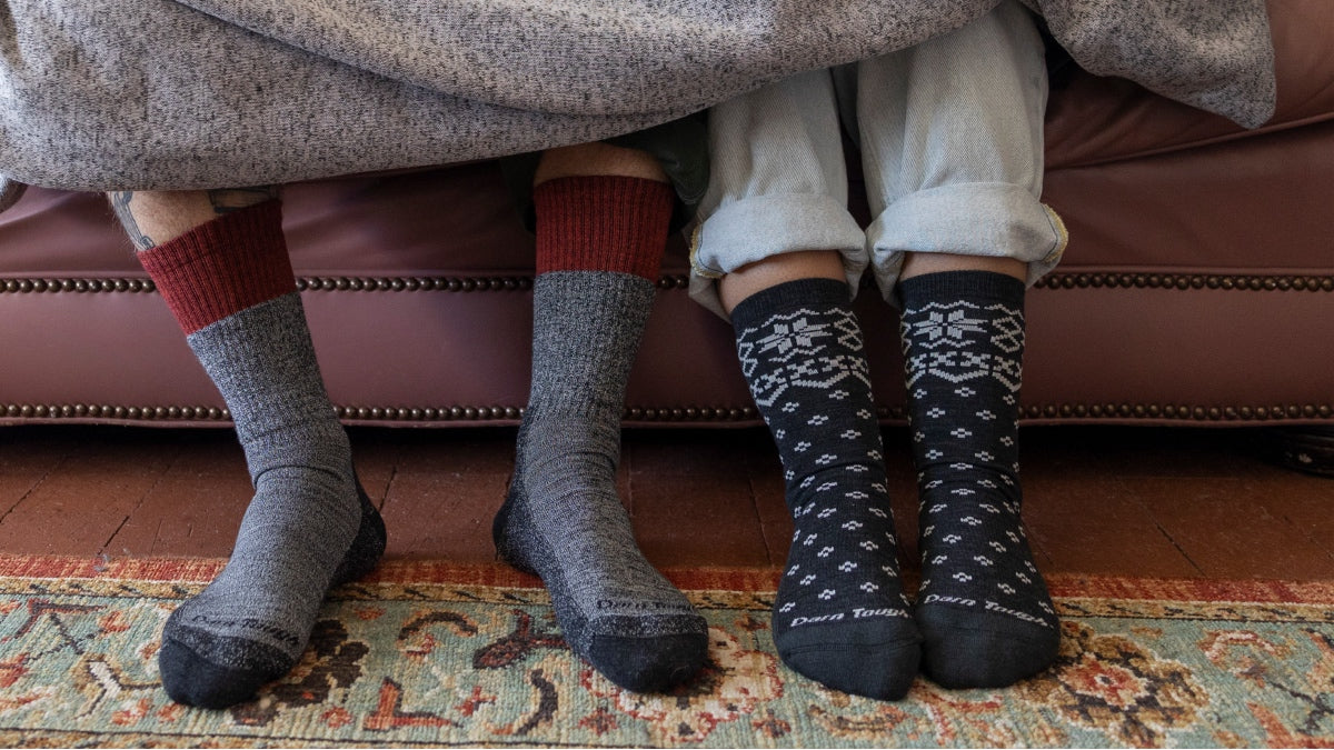Two people on couch under a blanket with sock-clad feet sticking out wearing the most comfortable socks