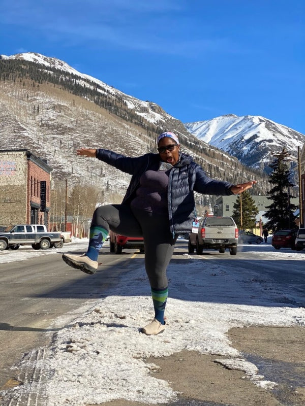 Mirna on a winter day making a goofy pose in front of snowy mountains