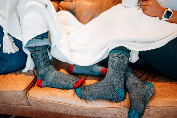 Two people sitting on a couch in Darn Tough Mountaineering Socks