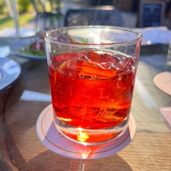 A Negroni, glimmering in the sunlight with beautiful red and orange hues