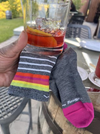 Mirna holding her Negroni up next to the Micro Crew Run Socks to show the matching colors