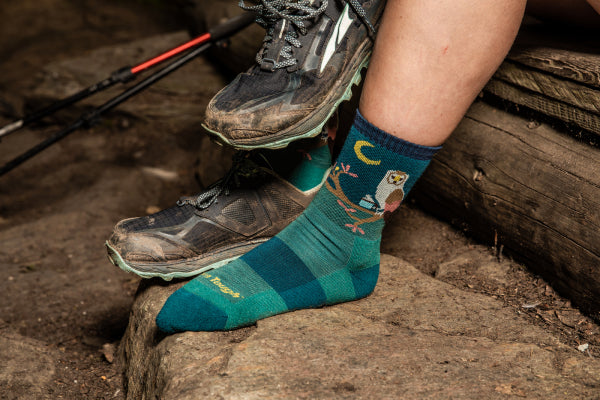 Person putting shoes on over Darn Tough owl socks