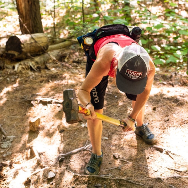 Woman wearing Darn Tough hat and using a tool to shape the trail