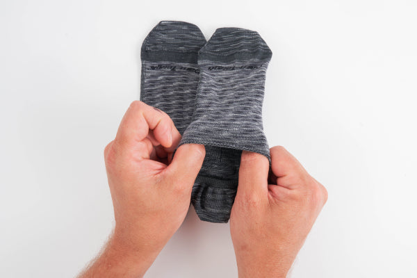 Hands holding no show socks showing the smooth, seamless edge - you can't even call it a cuff