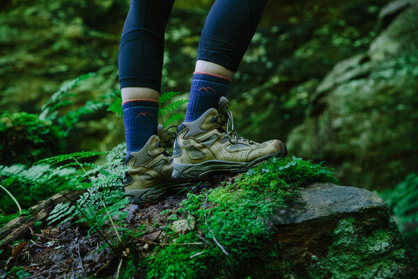 Hiker standing on trail wearing boots and darn tough socks for hikers