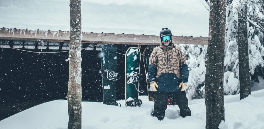 Max Holzman standing next to his workshop with some snowboards