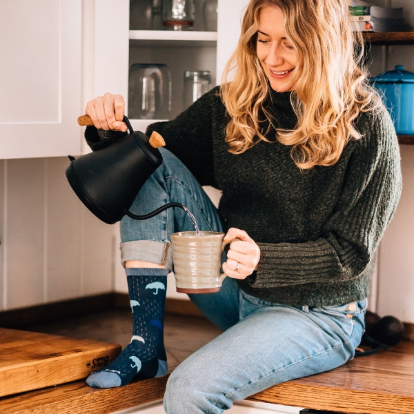 Woman seated on counter pouring a cup of tea