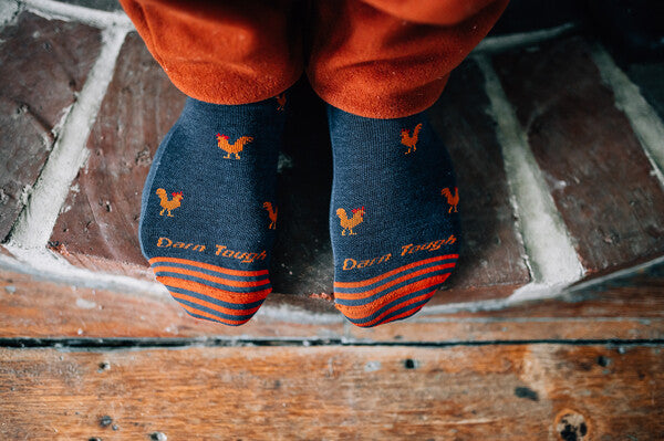 Feet on brick floor wearing the strut men's lifestyle socks from darn tough to keep their feet warm