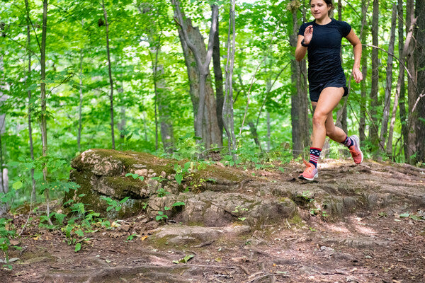 Woman running down a trail wearing darn tough men's running socks