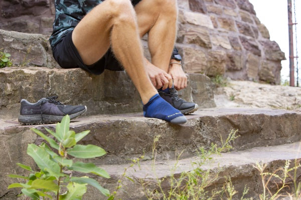 Josh seated on stairs in no show socks for running