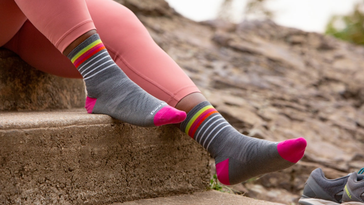 Close up of Mirna Valerio's feet wearing the Stride Micro Crew Run sock in gray with pink stripes