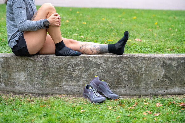 Person seated on wall with shoes off wearing black socks that are quarter crew height