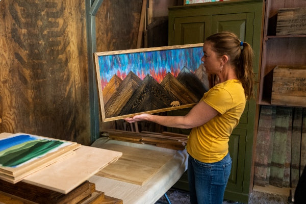 Megan working on a frame for one of her wooden signs, with a beautiful mountain vista