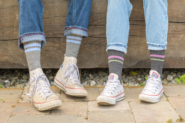 Two pairs of feet wearing matching men's and women's casual socks