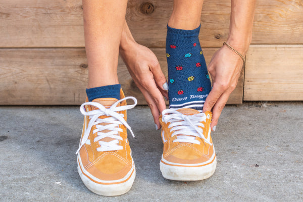 Close up of feet wearing lucky lady socks putting on low-top sneakers
