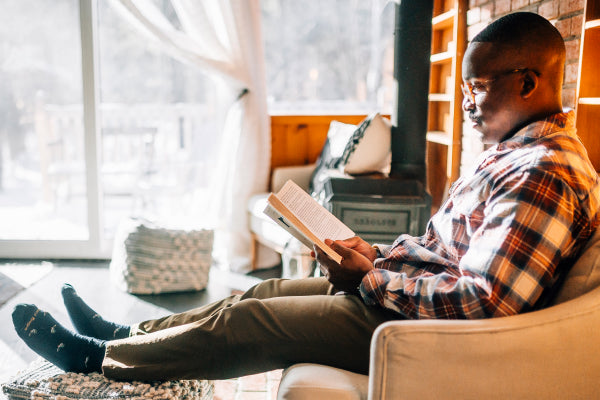 Person reading a book at home, feet up, wearing comfy lifestyle socks