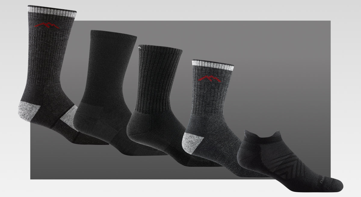 five examples of black socks from darn tough, on a grey background (of course)