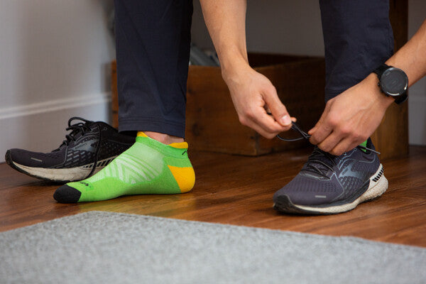 Running putting on sneakers over vibrant lime green socks