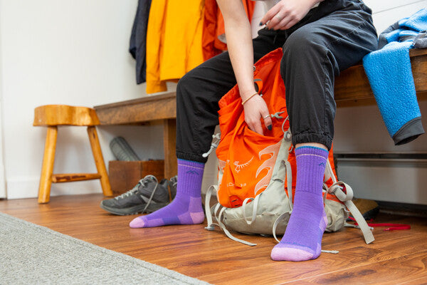 Person seated on bench, feet wearing bright purple hiking socks