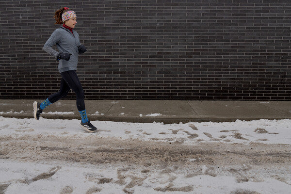 Woman running on a snowy street in proper cold weather gear