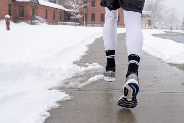 Runner on snowy street, wearing darn tough socks for all-weather Vermont running