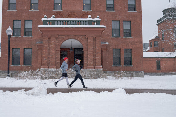 Two people running down a snowy street together