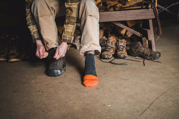 Person lacing up their boots over Darn Tough work socks, about to check the trees