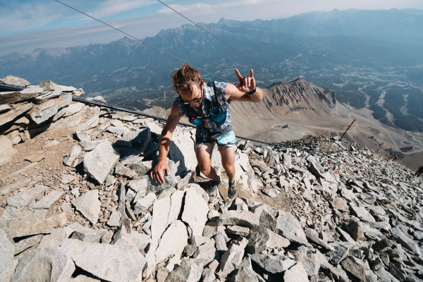 A racer throwing a "hang loose" hand sign as he heads up a steep slope