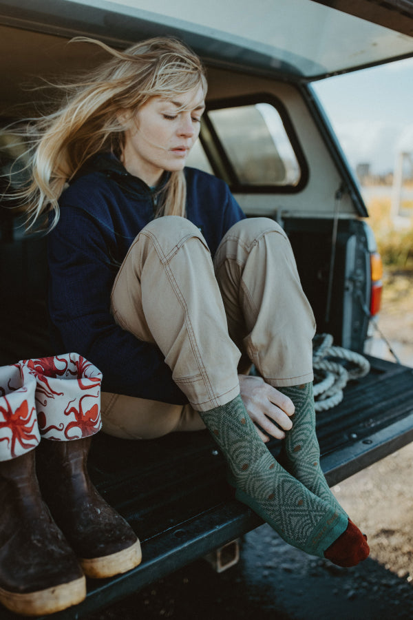 Claire seated and pulling on the Art Deco lifestyle socks from Darn Tough