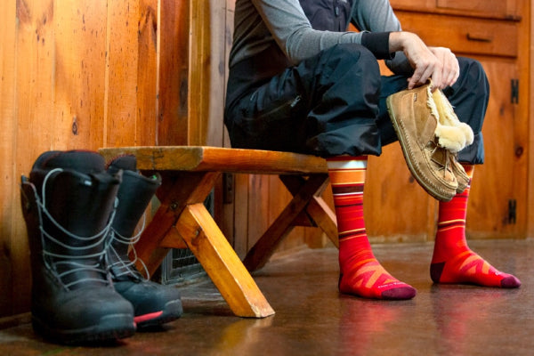 Snowboarder in the lodge wearing the bright red Snowpack socks from Darn Tough