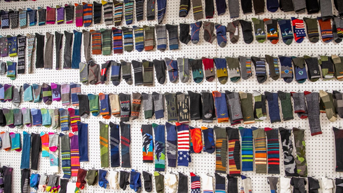 Many styles of Darn Tough socks hanging on a wall in the mill
