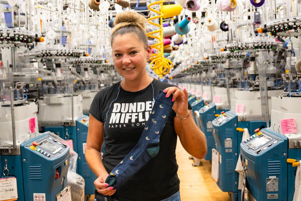 Rachel at the Mill holding the Duck Duck Moose sock with a fun duck design, with a few hidden moose