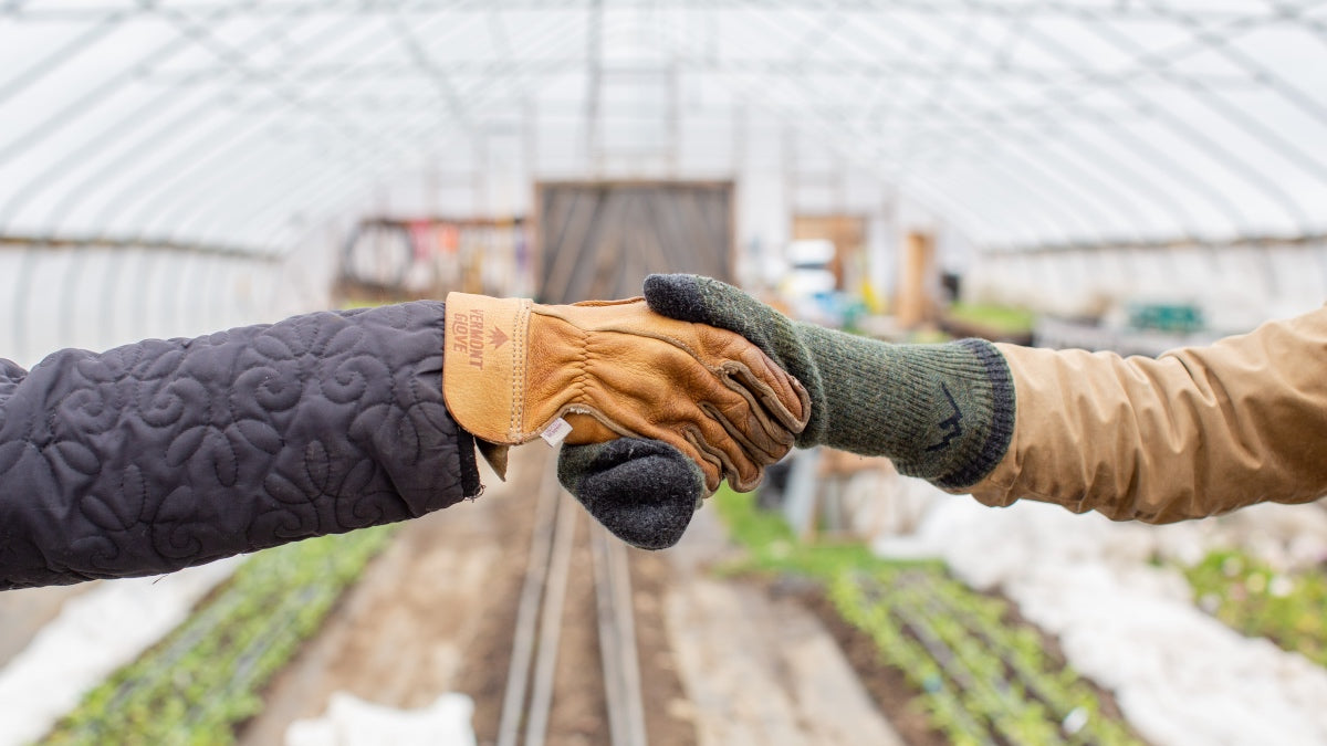 A glove-clad hand shaking hands with a sock-clad hand