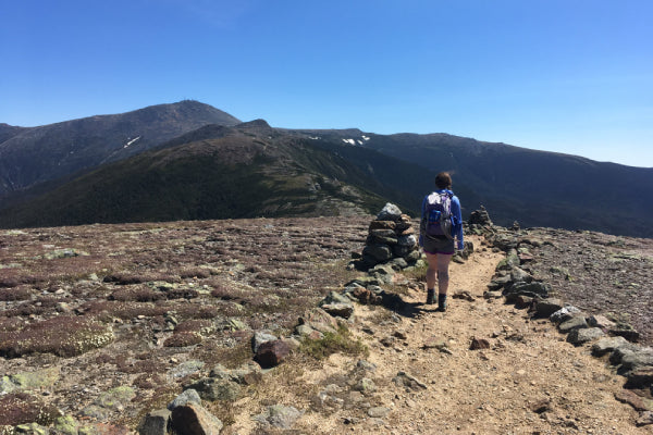 Hiker headed down Mt Eisenhower in NH, with view of Mt Washington