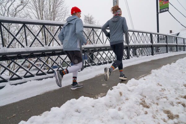 Two runners wearing Darn Tough Socks while it's snowing