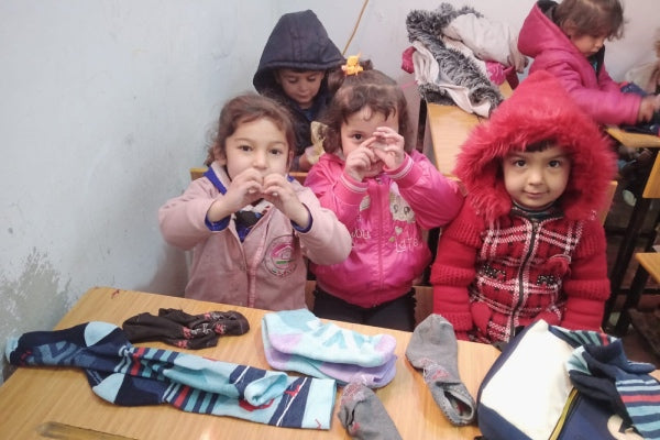 Children at Wisdom House making hearts with their hands