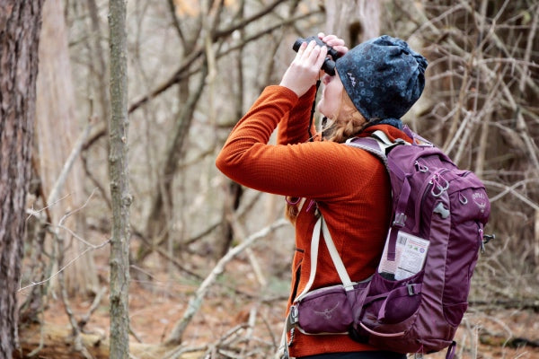 Hiker wearing a fleece and looking for birds through binoculars
