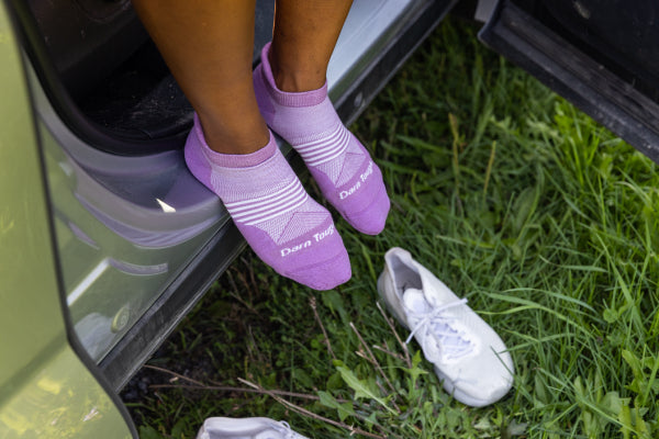 Runner sitting in the car putting her shoes on over her Darn Tough No Show Tab Running Socks