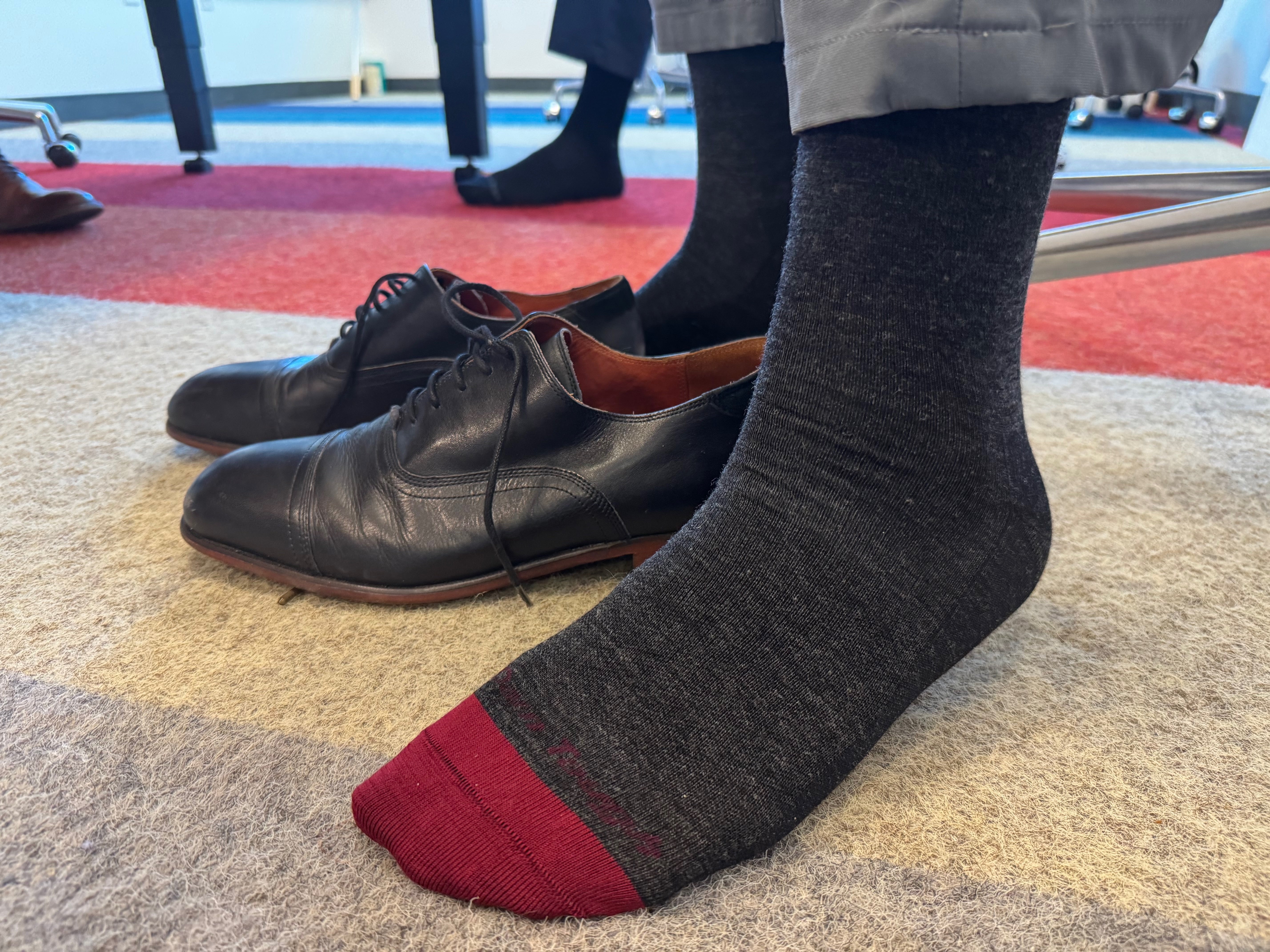 Feet wearing gray merino wool men's dress socks next to black dress shoes