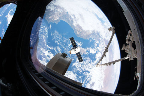External camera photographs a member of the Inspiration 4 crew looking at Earth through the SpaceX Dragon spacecraft’s cupola