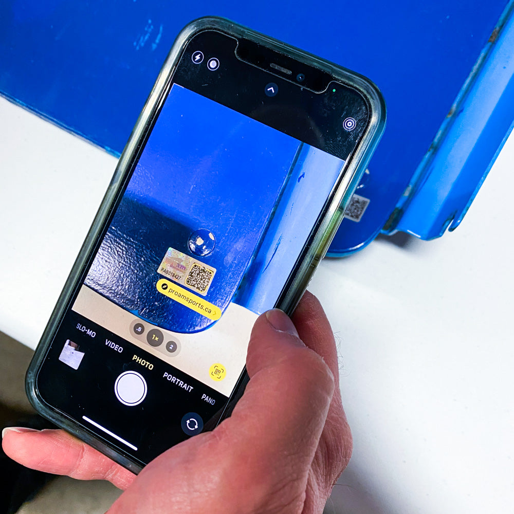 Image of someone holding an iphone and scanning a QR code on a hologram attached to a signed Rexall Place seatback. 