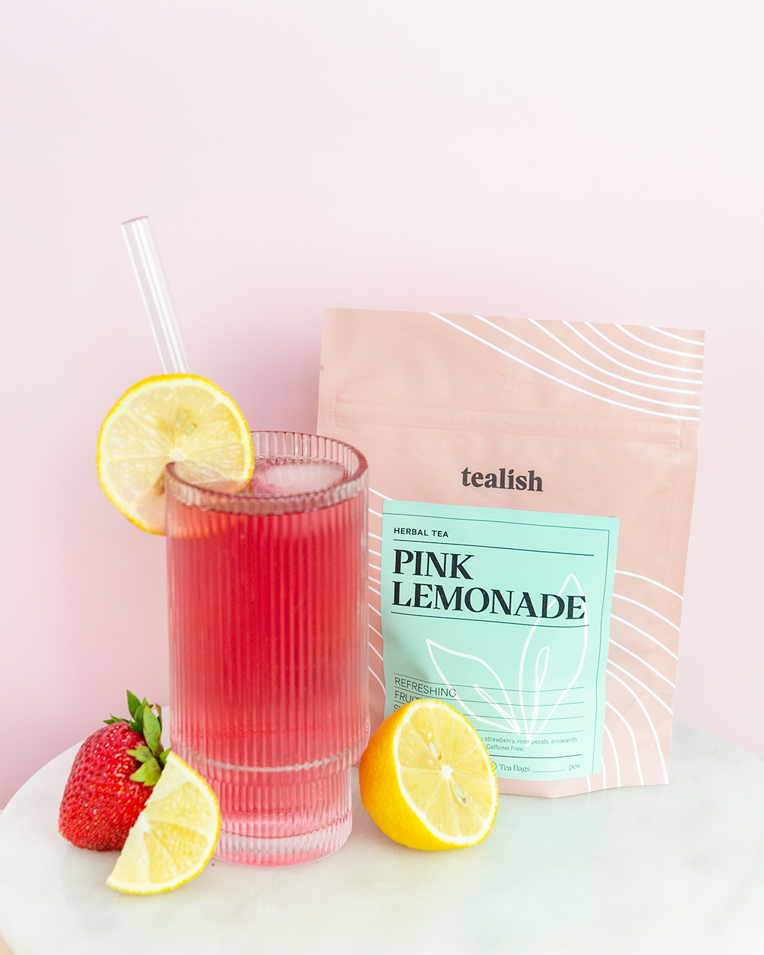 glass of iced pink herbal tea with pink lemonade tea pouch