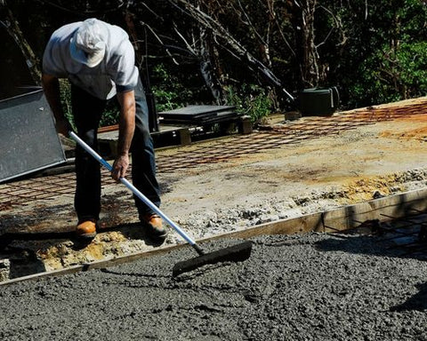 man using concrete tamping and spreading placer tool