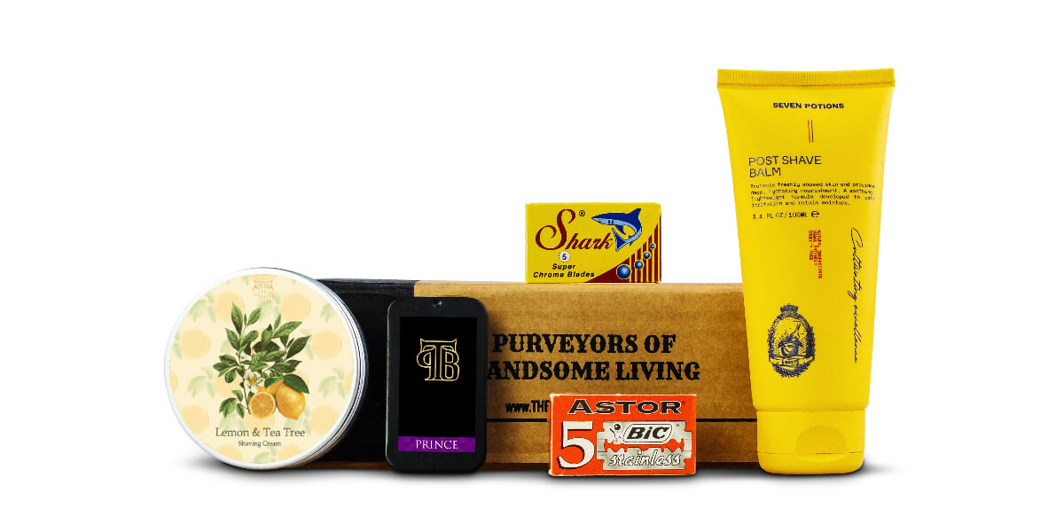 The Personal Barber January/Feb 2023 recurring shaving subscription box featuring lemon & tea tree shaving cream, Seven potions post-shave balm, Prince solid cologne, and Astor & Shark double-edge razor blades