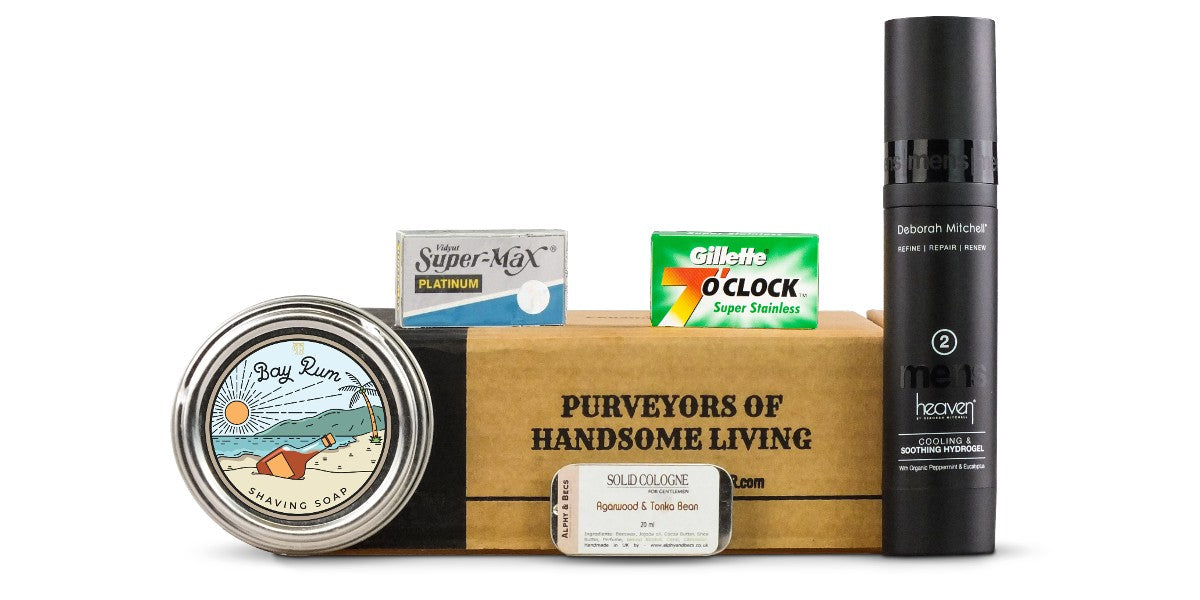 JulyAug shaving club subscription box featuring bay rum shaving soap, post-shave gel, solid cologne, and 10 replacement razorblades