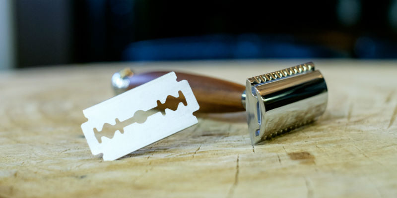 traditional safety razor and DE blade on wooden surface