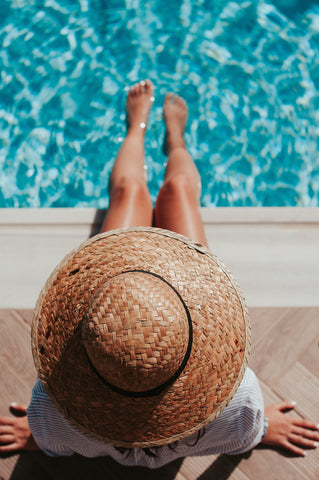 woman in a hat sitting by the pool