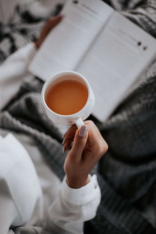 person drinking tea and reading book