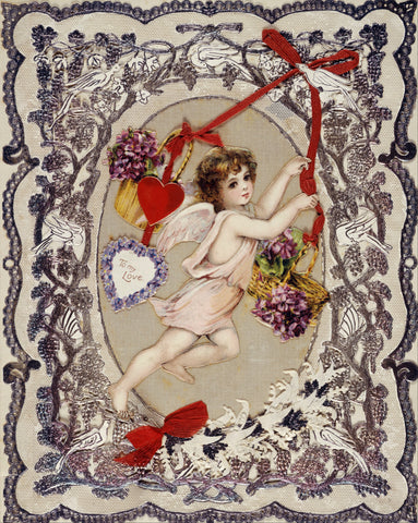 Cupid with a basket of flowers surrounded by glued-on hearts, floral embellishments, a velvet ribbon, and a velvet bow.
