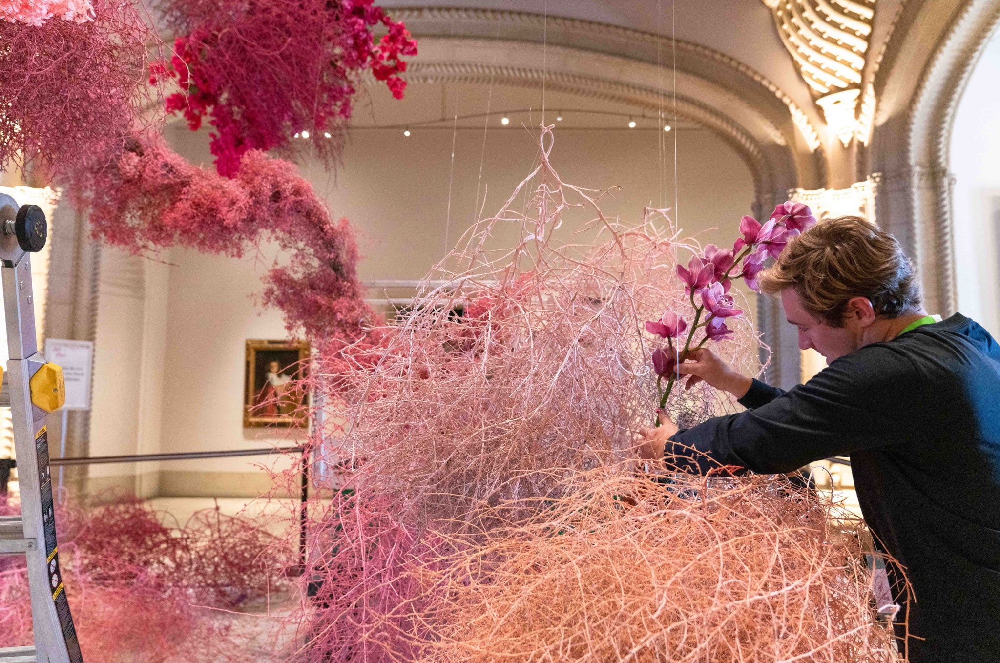Florist adjusts hanging tumbleweeds in the Rotunda Art Installation at SDMA